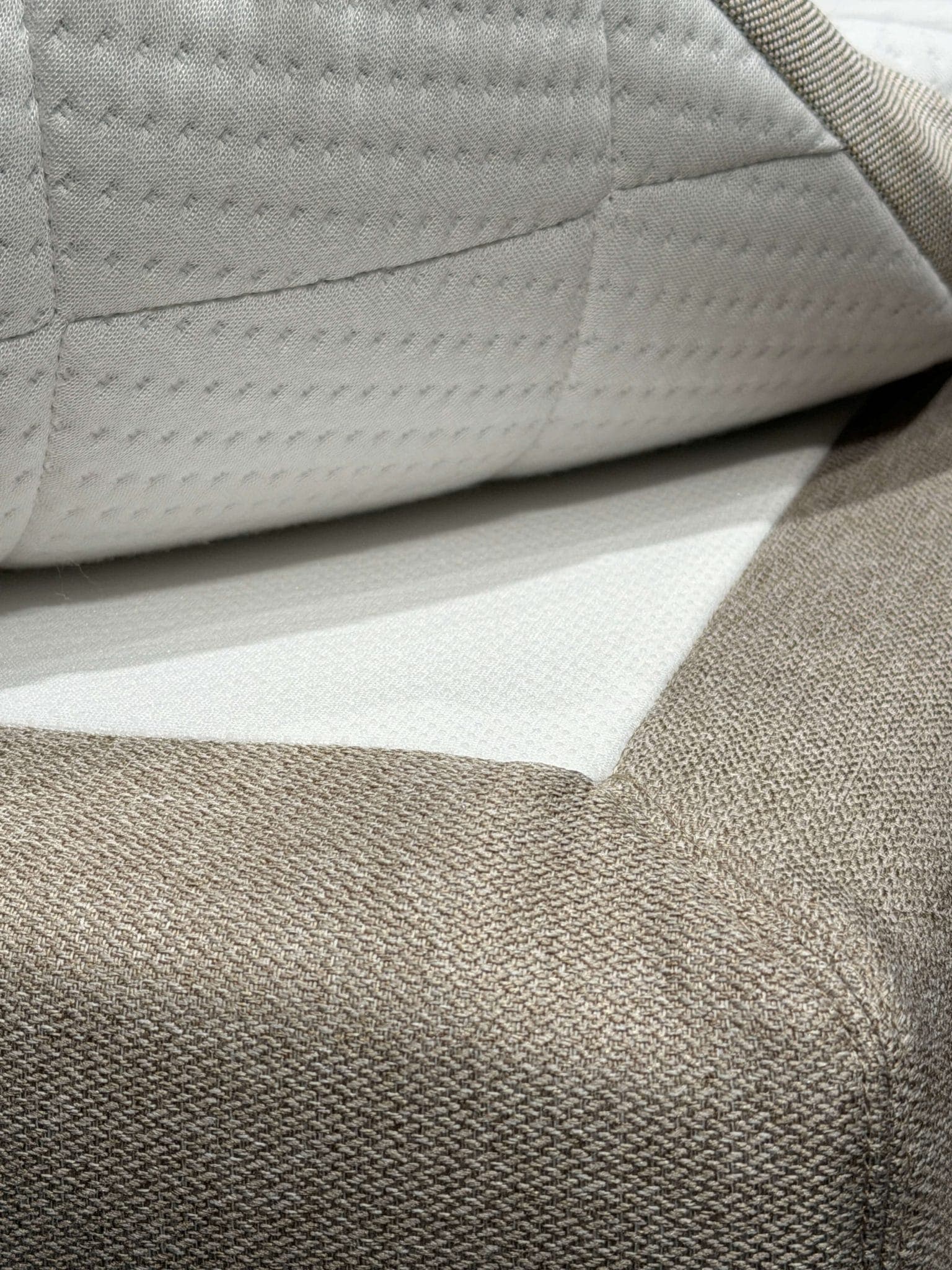 Angolo del topper sollevato per mostrare lo strato antiscivolo tra il topper e il rivestimento del letto