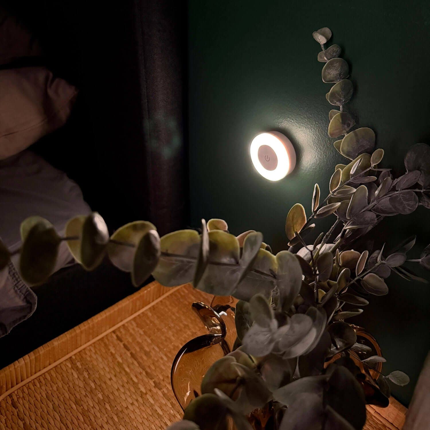 Lampada rotonda per l'allattamento che diffonde una luce soffusa sulla parete accanto al letto durante la notte