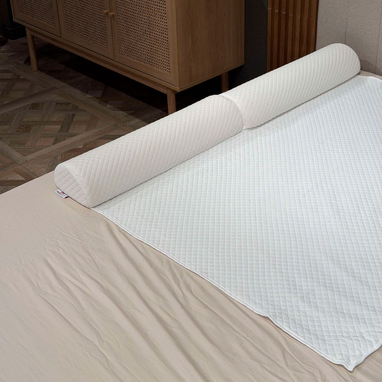 Barriera letto trapuntata in schiuma, inserita sotto il rivestimento bianco del topper lungo il bordo del letto
