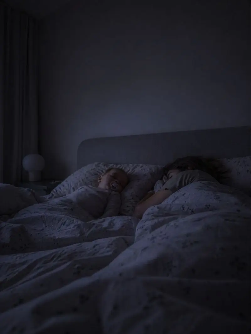 Due genitori e un bambino dormono vicini nel letto, nella luce soffusa della notte